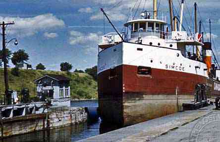 Westbound ship entering Lock 21.  The brow of the high embankment in the background is now just below the surface of Lake St. Lawrence at the western end of McDonald Island in the Long Sault Parkway.